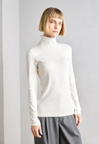 Light grey turtleneck top made of soft fabric, featuring long sleeves and a fitted design, paired with wide grey trousers.