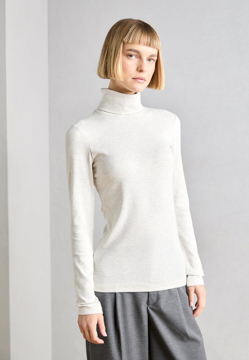 Light grey turtleneck top made of soft fabric, featuring long sleeves and a fitted design, paired with wide grey trousers.