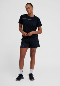 Black athletic t-shirt with a thin white stripe, paired with black shorts featuring a white logo. Worn with white socks and black shoes.