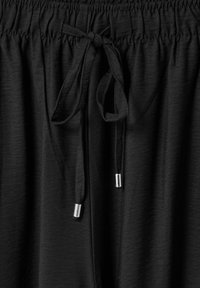 Zwarte joggers met een elastische tailleband, voorzien van een trekkoord met zilveren punten. Zachte textuur en lichtgewicht stof.