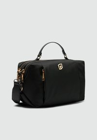 Borsa nera in nylon con una forma strutturata, dotata di manico superiore, accessori in oro e chiusura con zip. Include tracolla removibile.