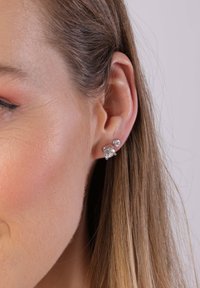 Silberne Ohrstecker mit zwei Zirkonia-Steinen, einer größer und einer kleiner, die eng zusammen gesetzt sind und einen geschichteten Look kreieren.