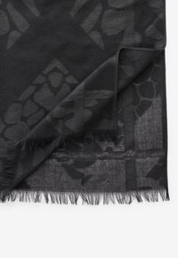 Black scarf featuring a textured pattern and fringed edges. Made of a lightweight material, it has a sheer, layered appearance.