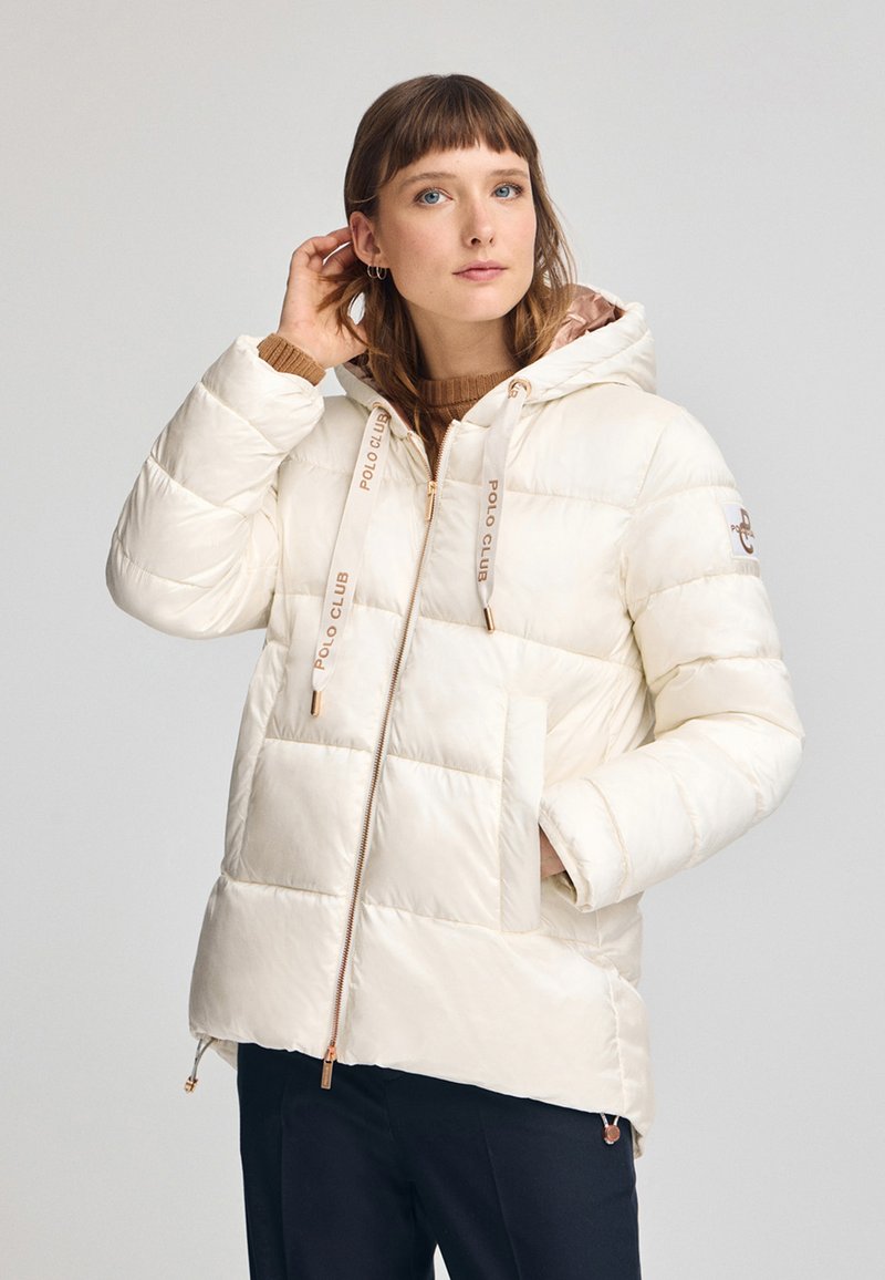 Kremowa kurtka puchowa z kapturem, z elementami w kolorze złota, pikowaną teksturą i akcentami logo. Dwie przednie kieszenie zapinane na zamek.
