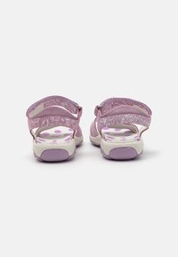 Rosafarbene Sandalen mit verstellbaren Riemen, strukturiertem Stoff und einer gepolsterten Sohle mit lila Punkten auf weißem Grund.