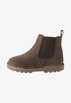 Stivale alla caviglia in suede marrone con pannelli elastici laterali, dettagli cuciti e suola in gomma con un motivo scanalato per la trazione.