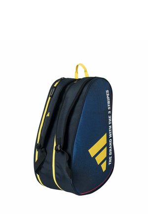Bolsa de raqueta de tenis azul y negra con detalles amarillos, compartimentos dobles, correas para el hombro y el texto "La Marca de las 3 Rayas" en el lateral.
