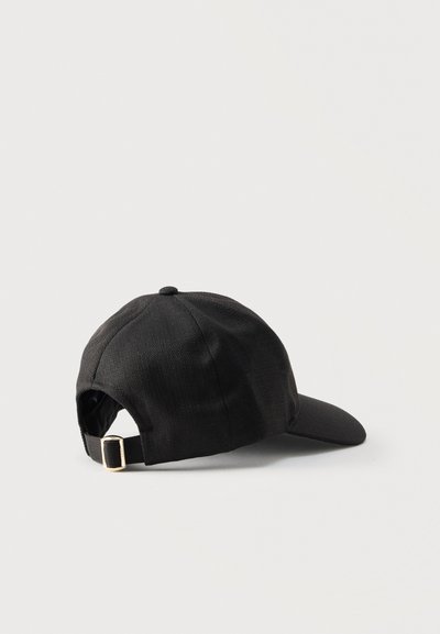 Gorra de béisbol de tela negra con correa ajustable y hebilla metálica vista desde atrás sobre un fondo claro.