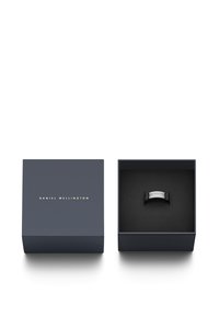 Crni prsten prikazan u tamnoj unutrašnjosti kutije. Vanjština kutije je mornarsko plava s natpisom "DANIEL WELLINGTON" zlatnim slovima. Glatki, minimalistički dizajn.