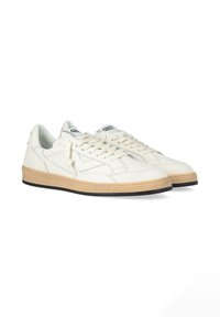 Des baskets en cuir blanc présentent une semelle en caoutchouc beige texturée, un détail perforé sur le bout, et un logo noir sur la languette.