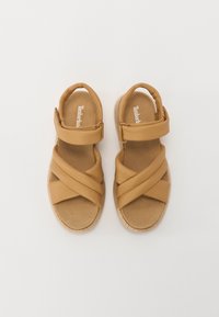 Kohvish värvi sandaalid ristirihmade disainiga, pehme ülemine osa ja Velcro kinnitusega. Pehmendusega sisetald ja tekstureeritud kummist välisrafter hea haardumise tagamiseks.