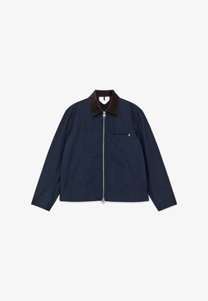 Tamsiai mėlyna medvilninė striukė su rudos spalvos kordurojo apykakle, priekyje užtrauktuku ir dviem šoninėmis kišenėmis; turi mažą krūtinės kišenėlę.