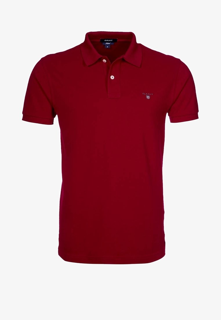 Polo rouge à manches courtes avec col, patte de boutonnage et petit logo GANT sur la poitrine gauche. La chemise est présentée sur un fond uni.