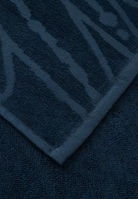 Serviette de bain bleu marine avec un design texturé et à motifs. Tissu en coton doux et absorbant avec un ourlet cousu le long du bord.