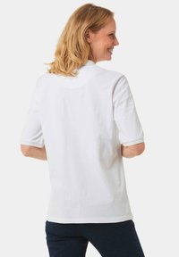 Weißes Baumwoll-T-Shirt mit kurzen Ärmeln, umgeschlagenen Säumen und rundem Ausschnitt. Glatte Textur; die Rückansicht zeigt ein minimalistisches Design.