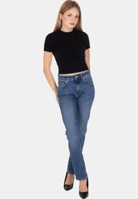 Top aderente nero a maniche corte abbinato a jeans blu a gamba dritta. I jeans presentano un classico design a cinque tasche e hanno un lavaggio medio.