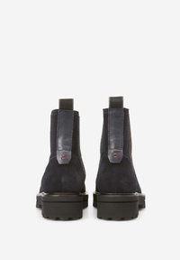 Bottines en suede noir avec des panneaux en cuir lisse contrastants, des inserts élastiques sur les côtés et des semelles en caoutchouc, offrant un design minimaliste.