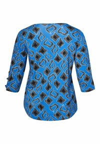 Zila blūze ar ģeometrisku rakstu melnā un gaiši zilā krāsā. Garas piedurknes ar aprocēm un apaļu apkakli. Mīksta auduma tekstūra.
