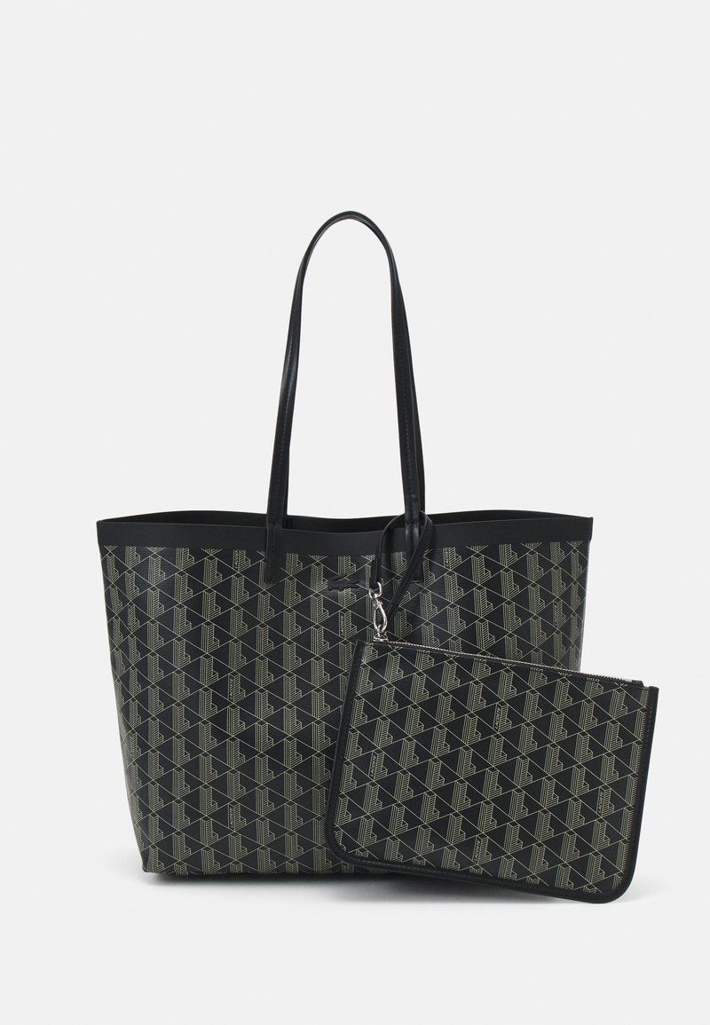 Czarna torba na ramię z geometrycznym wzorem w odcieniu beżu; posiada długie uchwyty i zawiera pasującą saszetkę na zamek. Wykonana z trwałego materiału.