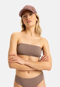 Hnedý textúrovaný bandeau bikini top a zodpovedajúce vysoké nohavičky, doplnené svetlohnedou šiltovkou s logom.