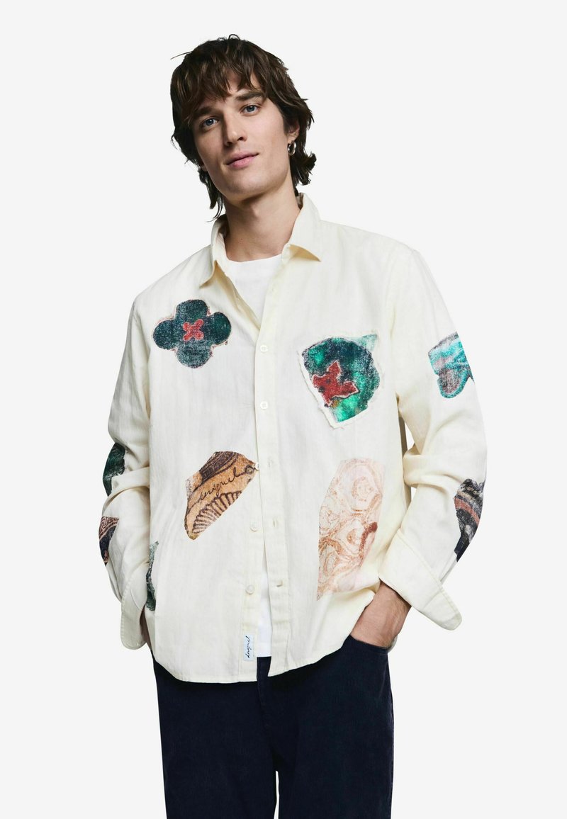 Heledast linast triiksärk, millel on erinevate tekstuuridega kangast lille- ja abstraktsete kujudena applikaadid, millel on selged mustrid ja värvid.