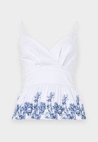 Witte katoenen top met een v-hals, verstelbare bandjes en een uitlopende zoom versierd met blauwe bloemenbroderie langs de onderkant.