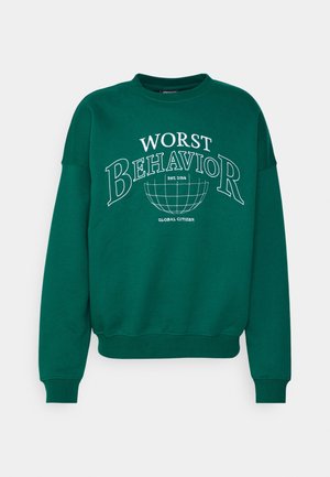 Grünes Sweatshirt mit Rundhalsausschnitt und weißem Text "WORST BEHAVIOR" über einer Globus-Grafik sowie kleinem Text "EST. 2014" und "GLOBAL CITIZEN"