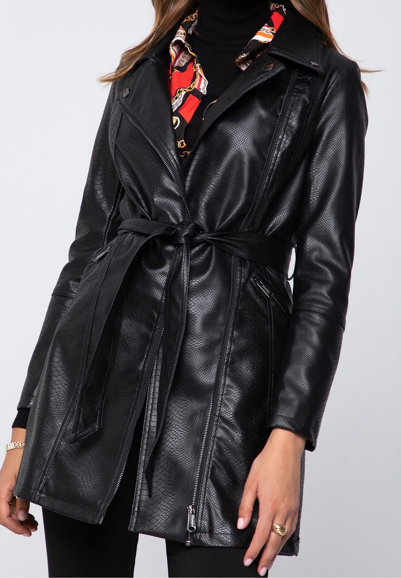 Manteau trench en simili cuir noir avec un motif en fausse peau de serpent texturé, taille ceinte, col à revers et poches zippées sur les côtés.