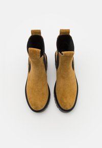 Stivaletti in suede marrone con pannelli laterali in elastico nero e linguette per il tiraggio, caratterizzati da una superficie testurizzata e suole in gomma.