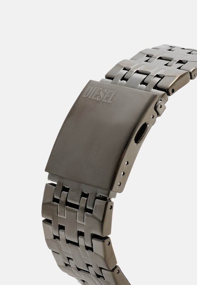 Montre en métal avec une finition gris foncé, présentant un boîtier rectangulaire massif et un design de bracelet à maillons. Équipée d'une fermeture à clapet et d'une gravure de logo.