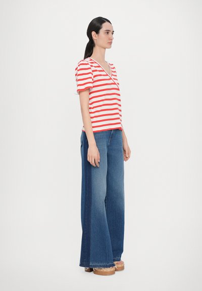 Red and white striped short-sleeve top with a V-neck, paired with wide-leg blue denim jeans. Wood-soled clogs with a textured finish.