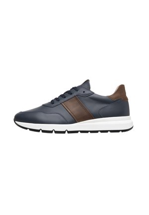 Sneaker in pelle blu navy con dettagli in marrone, suola intermedia bianca, suola esterna nera e sei fori per i lacci. Presenta una finitura liscia e texturizzata.