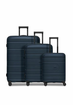 Ensemble de valises rigides navy de trois tailles avec surface texturée, poignées rétractables noires et roues pivotantes pour une mobilité aisée.