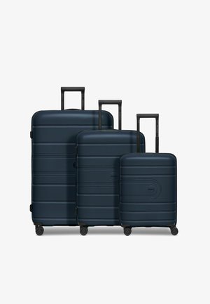 Set di valigie rigide navy di tre dimensioni con superficie testurizzata, manici retrattili neri e ruote girevoli per una facile mobilità.