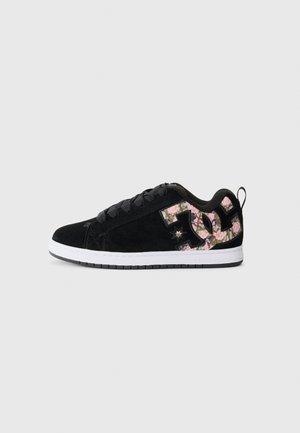 Black suede sneaker with a white rubber sole. Features a large floral-patterned logo on the side and black laces. Low-top design.