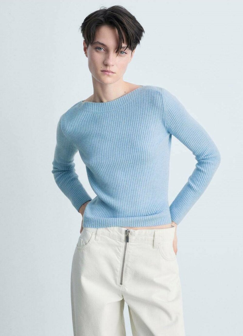 Maglione azzurro chiaro a coste con maniche lunghe e scollatura ampia, abbinato a pantaloni bianchi sporchi a vita alta con chiusura a zip.