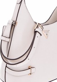 Borsa a tracolla bianca con texture e accenti dorati, caratterizzata da un design curvo, tracolla regolabile e etichetta triangolare con marchio.