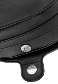 Czarna skórzana torba o okrągłym kształcie, z teksturowaną powierzchnią, przeszyciami oraz srebrnym, wytłoczonym guzikiem do zapięcia.