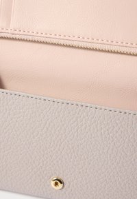 Two-tone leather wallet in soft pink and light gray. Features textured surfaces and a gold-toned snap closure. Stitched detailing visible.
