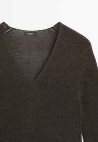 Ciemnobrązowy dziergany sweter z dekoltem w kształcie litery V i długimi rękawami, pokazujący fakturę tkaniny oraz małą czarną metkę wewnątrz kołnierza.