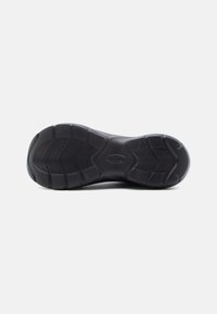 Μαύρη σόλα παπουτσιού από καουτσούκ με υφασμένα σχέδια, ραβδώσεις και λεία επιφάνεια. Καλά καθορισμένα τμήματα για πρόσφυση και σταθερότητα.