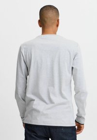 Langärmliges graues T-Shirt aus weicher Baumwolle. Mit Rundhalsausschnitt, schmalen Ärmeln und einer glatten Textur ohne sichtbare Muster oder Grafiken.