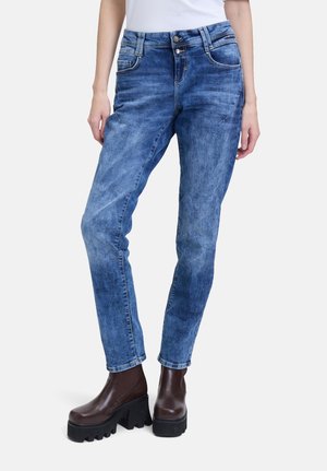 Jeans in denim blu aderenti con una finitura sbiadita, design a cinque tasche e chiusura con bottone in metallo. Indossati con stivali platform marroni spessi.