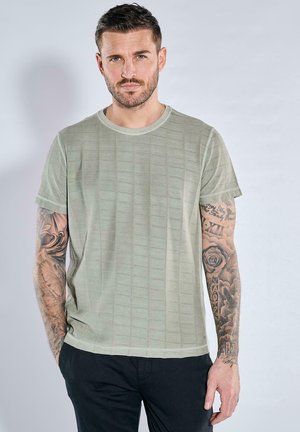 Hellgrünes T-Shirt mit kurzen Ärmeln und einem strukturierten Rautenmuster. Weicher Stoff, runder Halsausschnitt und leicht lässige Passform.