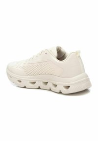 Zapatilla ligera beige con parte superior de malla, acentos texturizados y una suela gruesa que presenta bolsillos de aire visibles para mayor amortiguación.