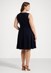 Navy blue sleeveless dress with a fitted bodice, flared skirt, and a back zip. Smooth texture with clean lines and no visible patterns.