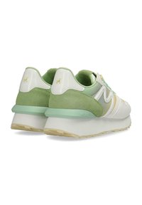 Sneaker bianche e verde chiaro con una finitura liscia e testurizzata, dotate di una suola spessa e accenti di branding discreti sul tallone.