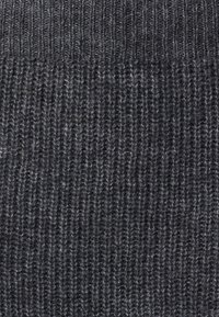 Strikket grått stoff med ribbestruktur. Mørkegrå toner med lysere flekker, som viser et mykt og elastisk materiale.