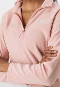 Fleece-pullover i mjuk rosa, med kvart-zip krage, diskret logo och långa ärmar med åtsittande manschetter. Slät textur.