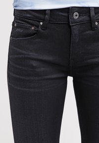 Svarta denimjeans med slim fit, med subtil blekning, framfickor och metallhardware i midjan. Accenterad med en logg etikett.